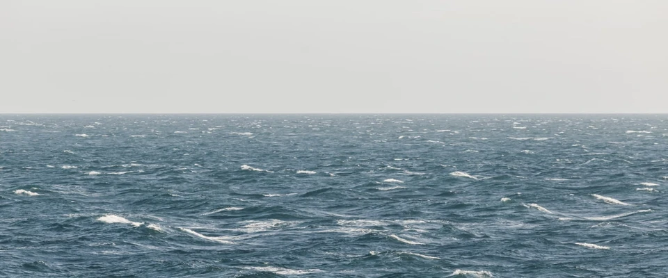 Open sea with rolling waves under an overcast sky, illustrating wind conditions at sea.