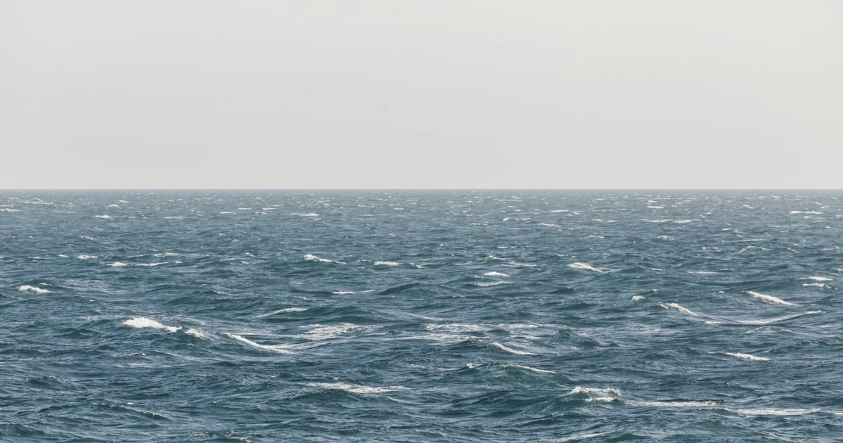 Open sea with rolling waves under an overcast sky, illustrating wind conditions at sea.