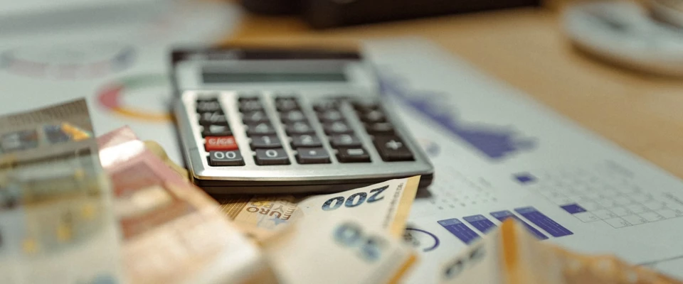 Calculator and financial documents on a desk, used to review and calculate boat ownership expenses.