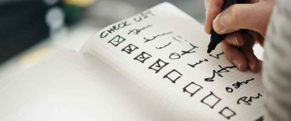 Hand checking items on a boat inventory checklist with a pen.