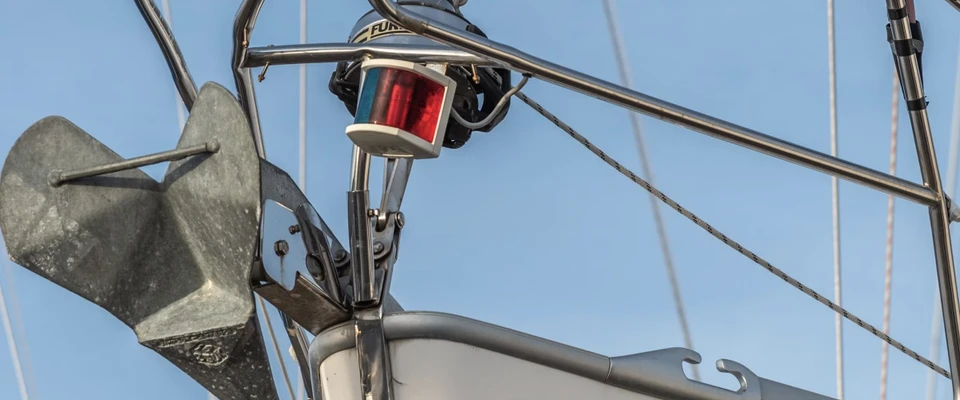 Red navigation light mounted on a sailboat's rigging against a blue sky.
