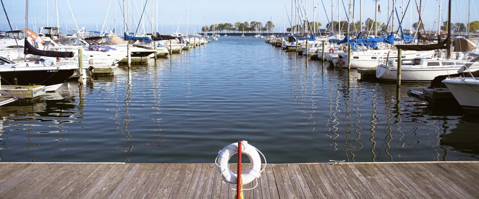Marina full of moored boats with a lifebuoy hanging on the wooden dock.