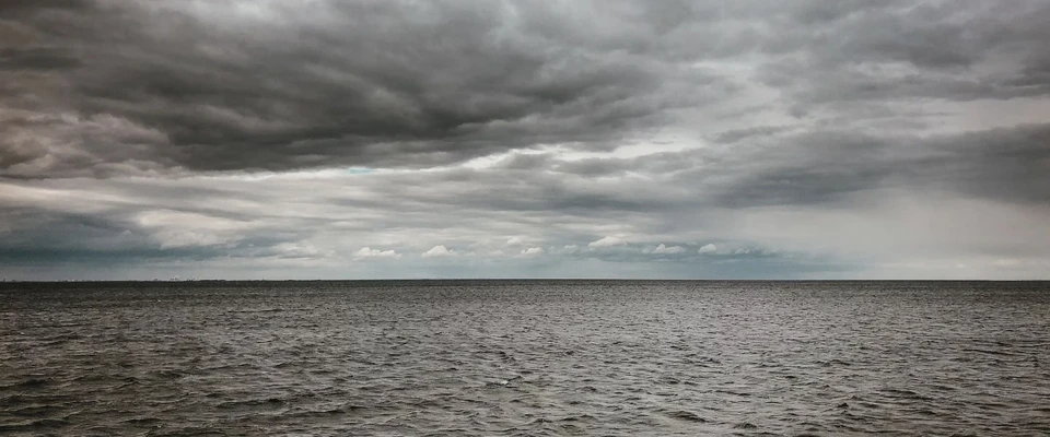 Dark, layered clouds gathering over a choppy sea, illustrating changing marine weather conditions.