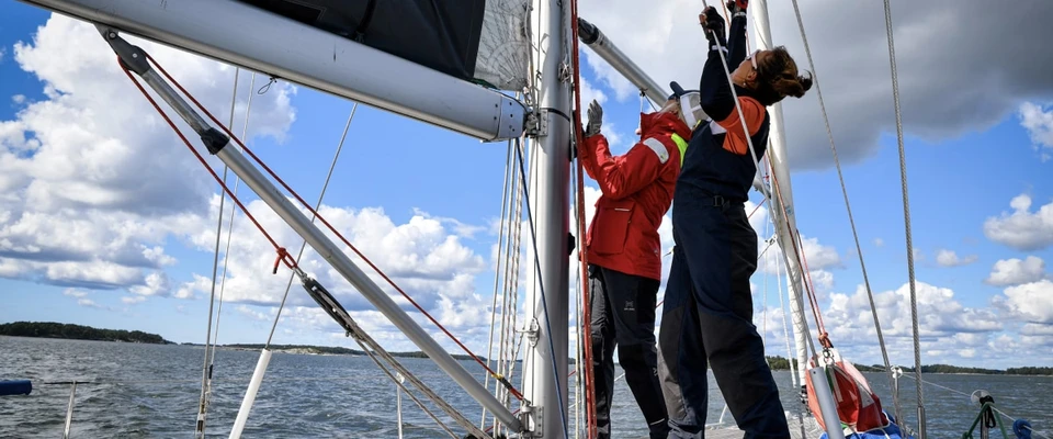Sailing crew working together on deck while handling the yacht's rigging and sails.