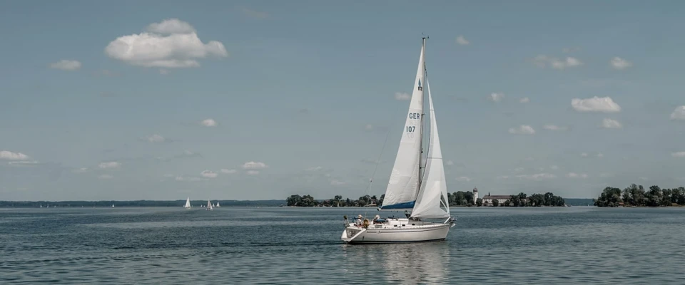 Sailboat underway on open water beneath a partly cloudy sky, illustrating sailing in changing wind conditions.