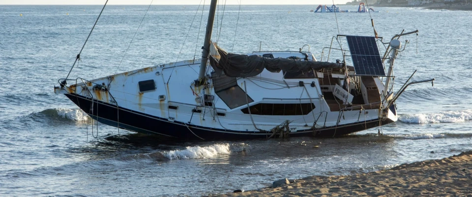 Sailboat listing heavily in the water after an incident, illustrating the importance of recording boating accidents.