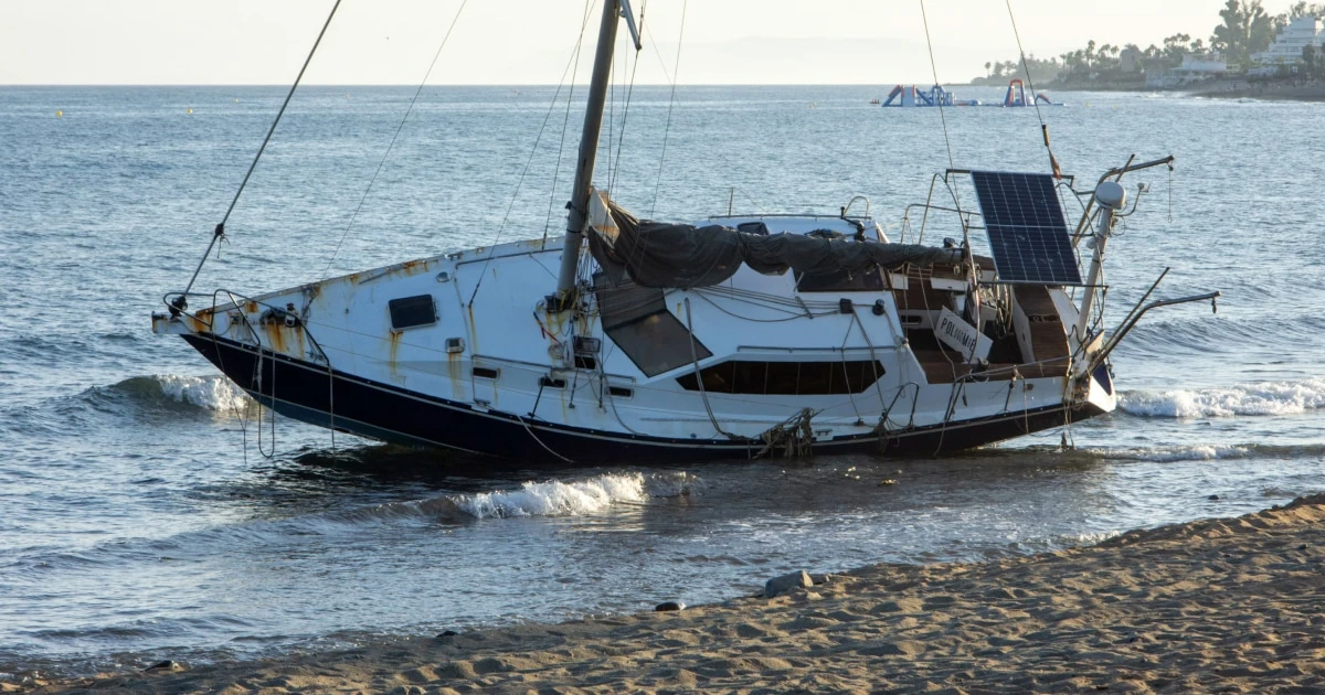 Sailboat listing heavily in the water after an incident, illustrating the importance of recording boating accidents.