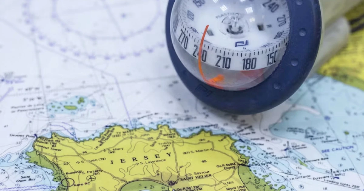 Hand-bearing compass lying on a nautical chart to determine a bearing at sea.