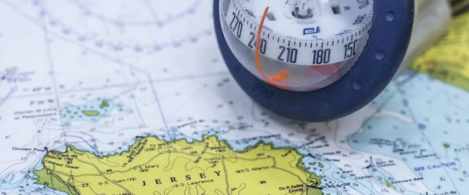Hand-bearing compass lying on a nautical chart to determine a bearing at sea.