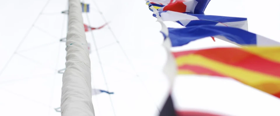 Colourful international maritime signal flags hanging from a sailboat's rigging.