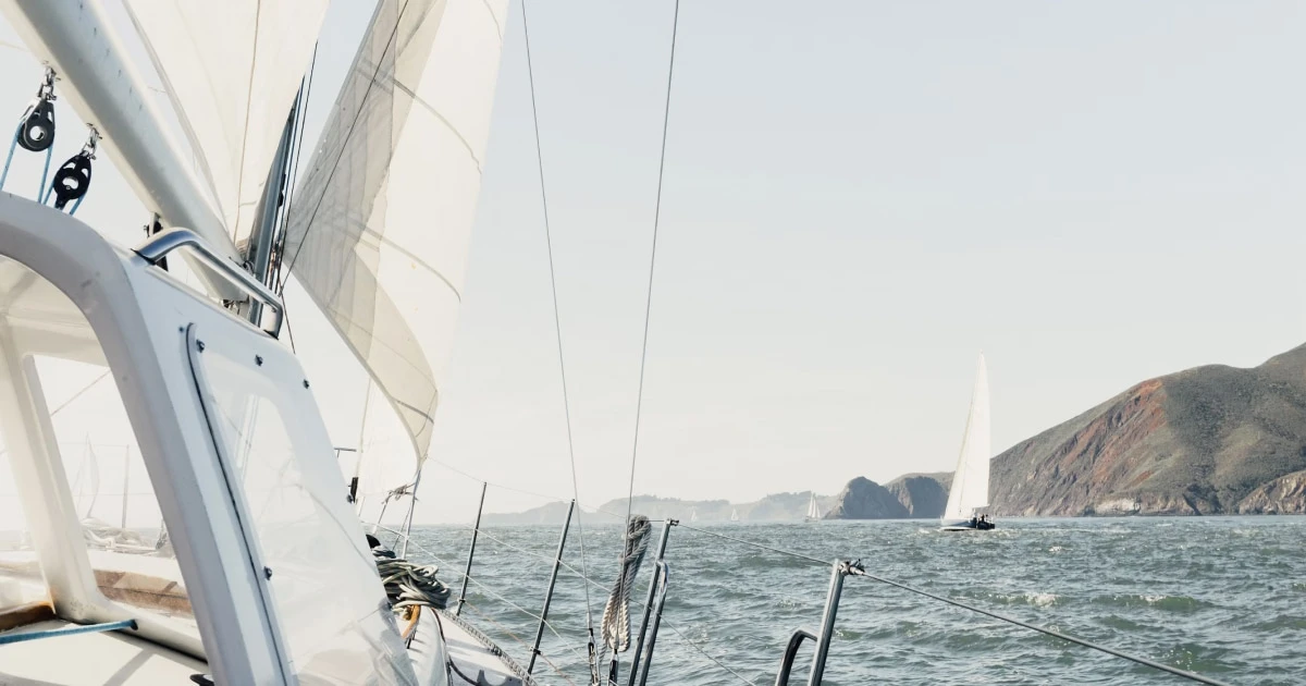View from aboard a sailboat approaching a rocky coastline.