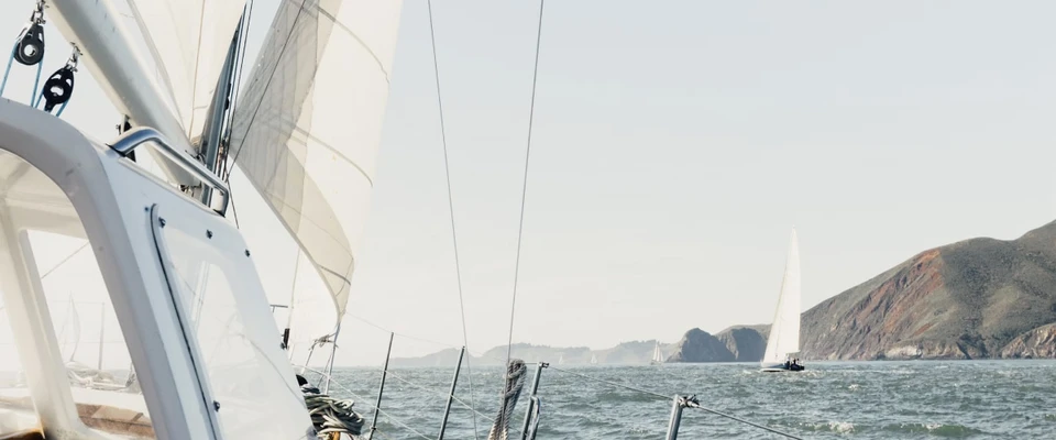 View from aboard a sailboat approaching a rocky coastline.