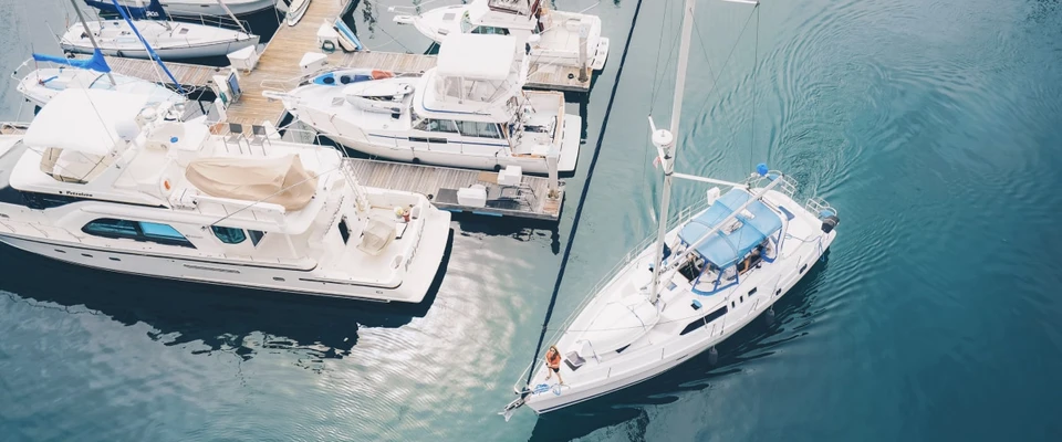 Aerial view of sailboats and motorboats in a turquoise marina.