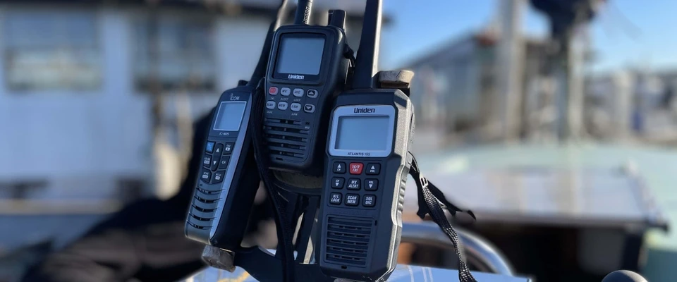 Handheld VHF marine radios in their holders on a boat.
