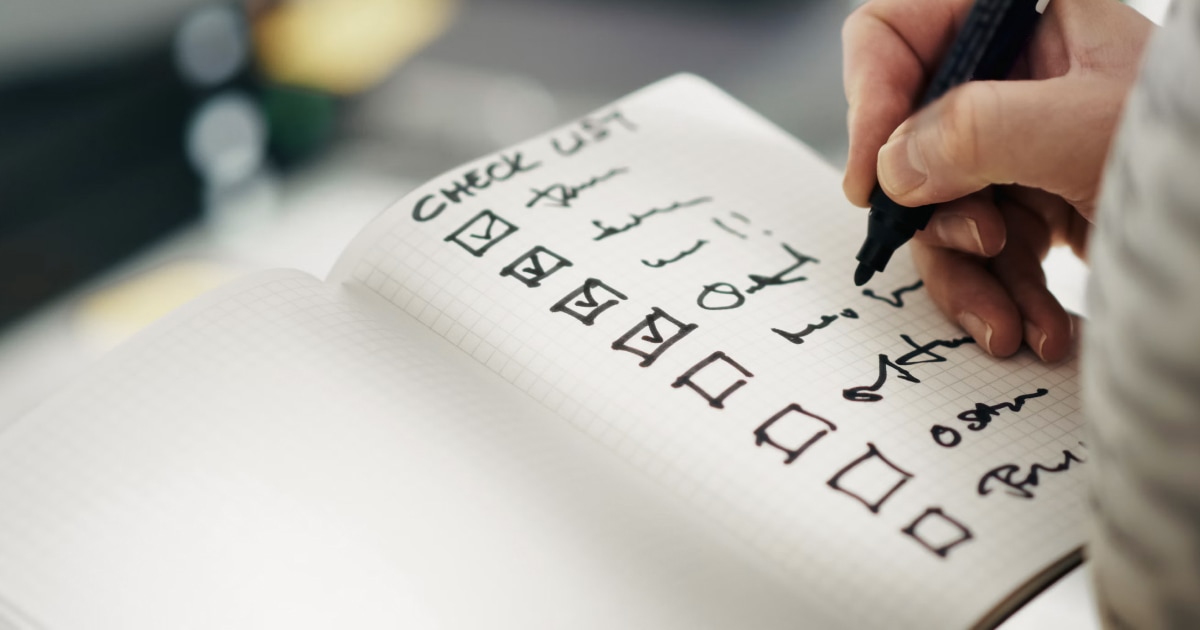 Hand checking items on a boat inventory checklist with a pen.