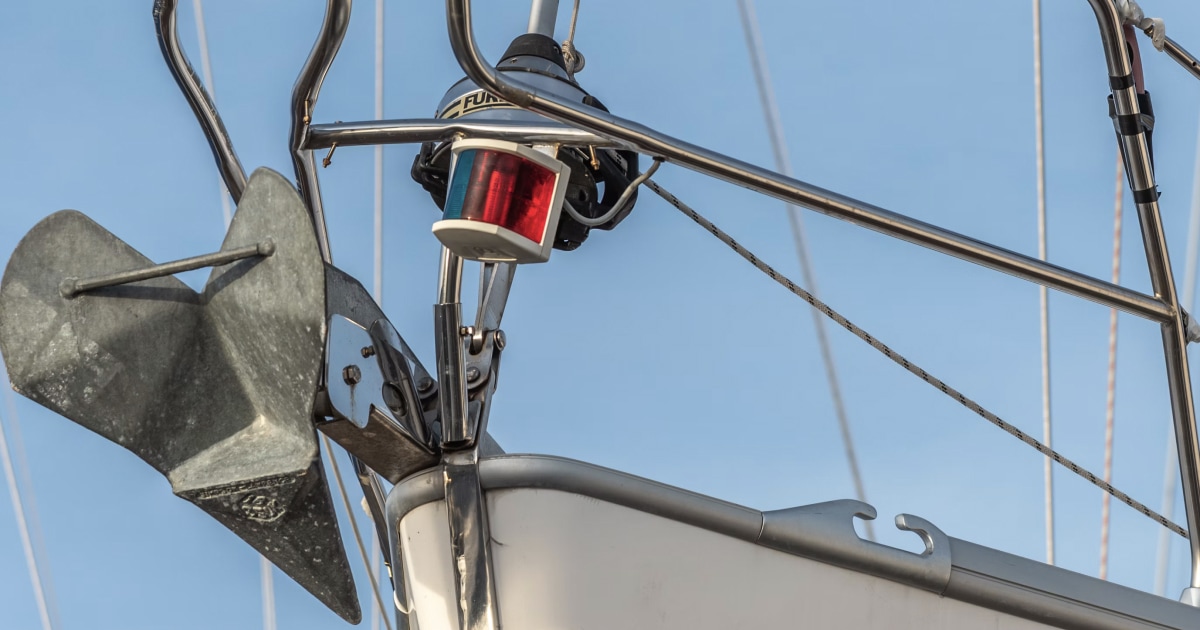 Red navigation light mounted on a sailboat's rigging against a blue sky.