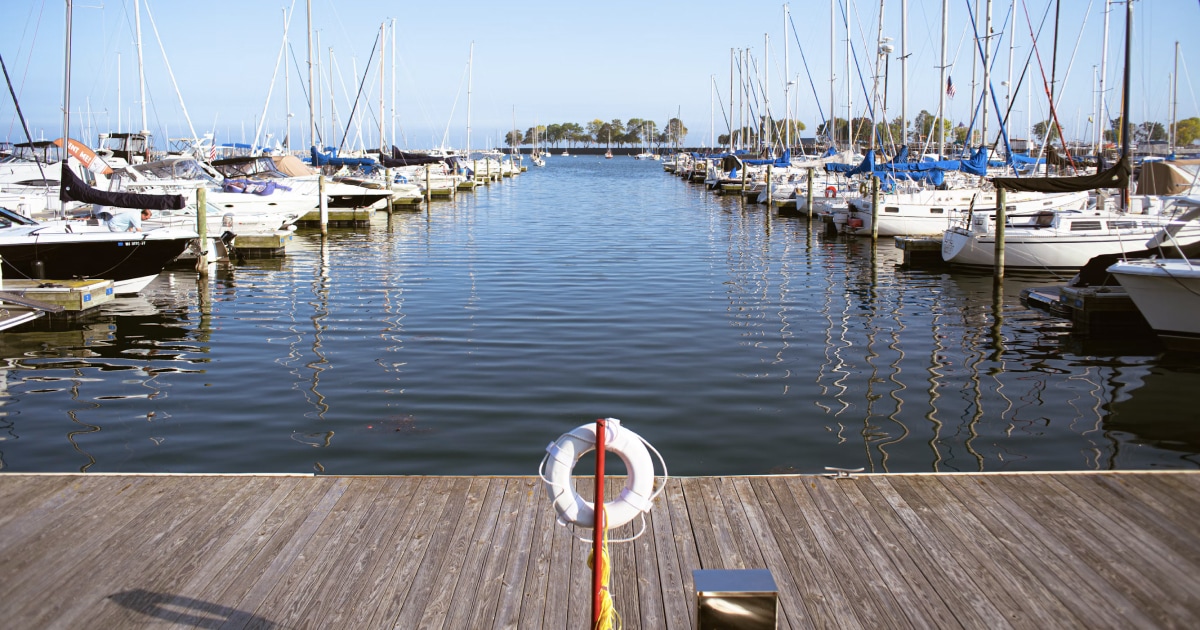 Marina full of moored boats with a lifebuoy hanging on the wooden dock.