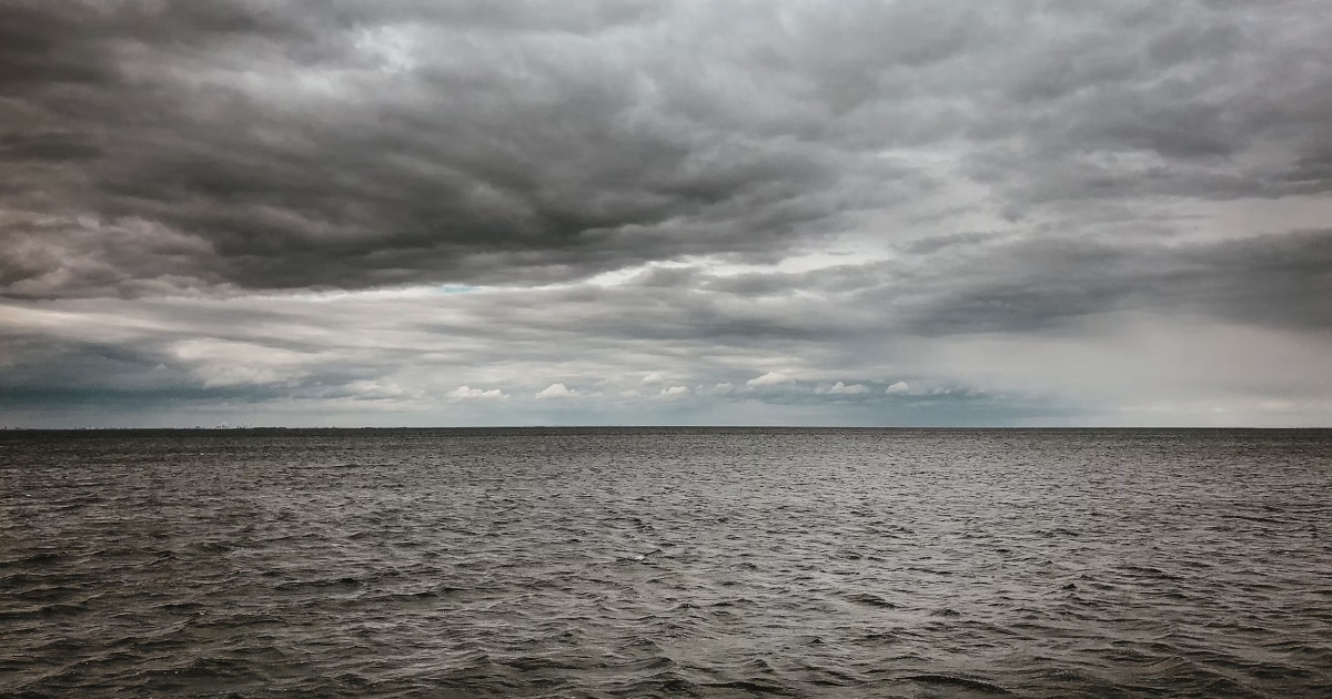 Dark, layered clouds gathering over a choppy sea, illustrating changing marine weather conditions.
