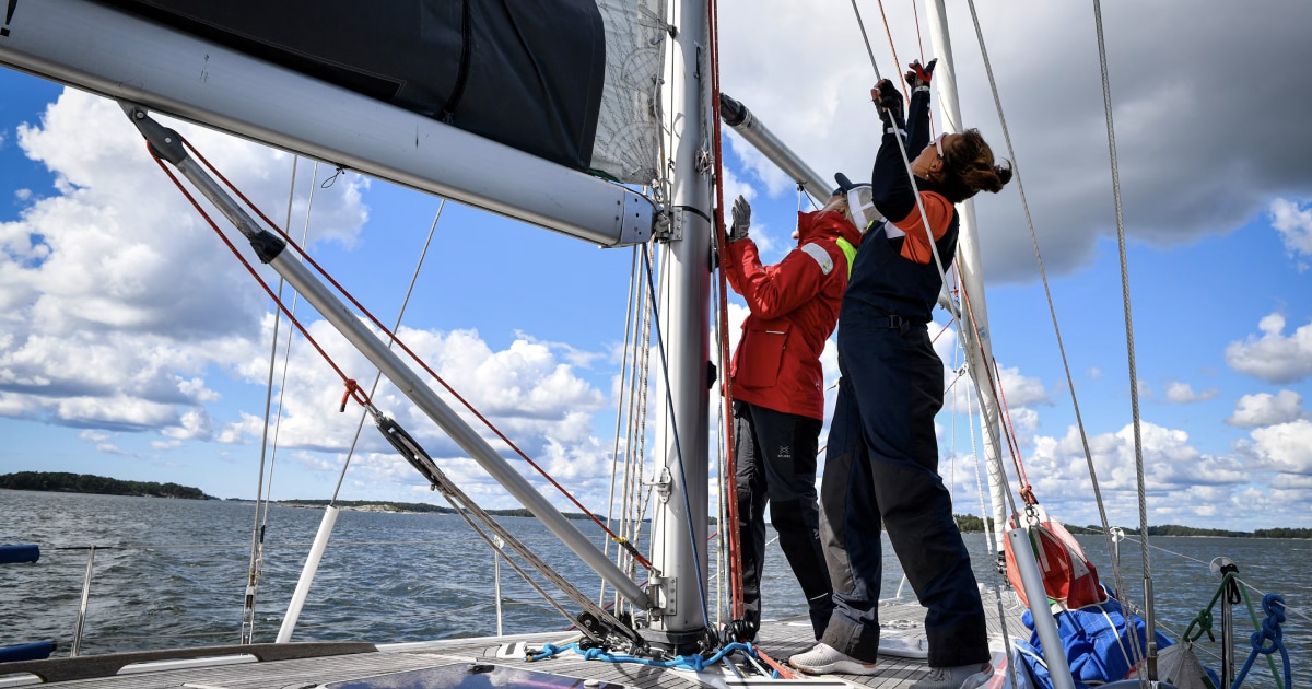 Sailing crew working together on deck while handling the yacht's rigging and sails.