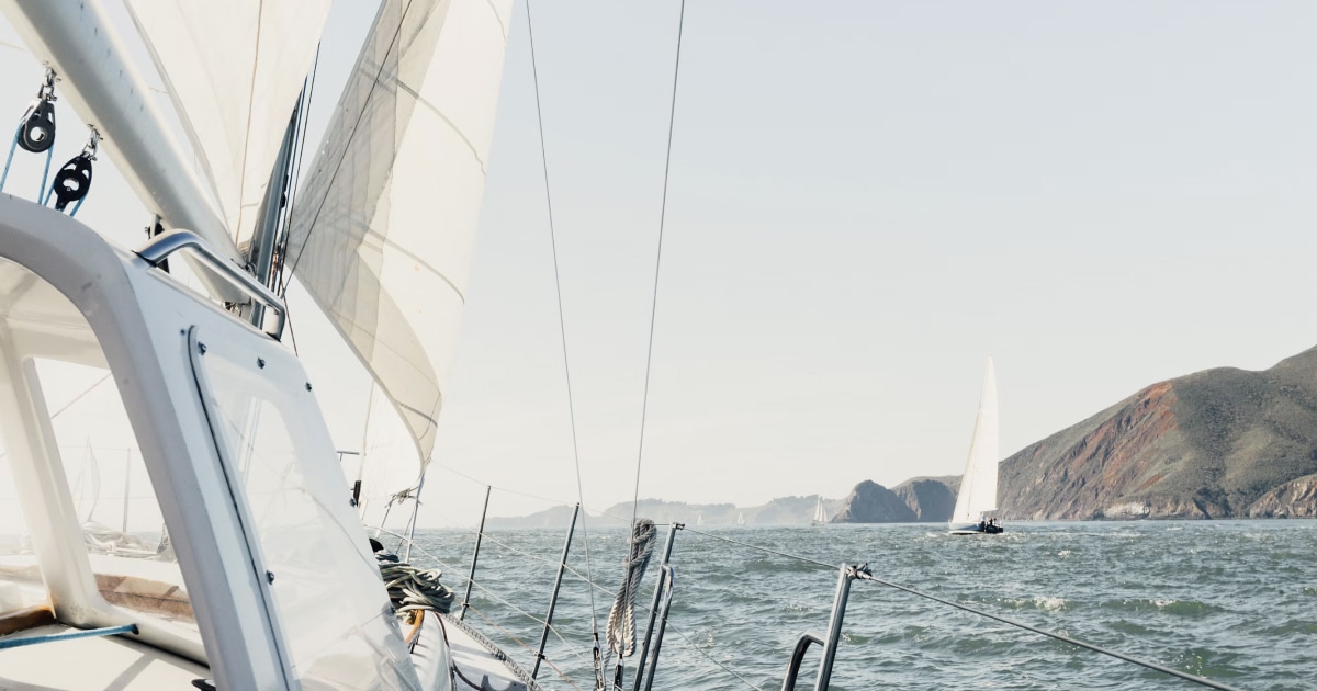 View from aboard a sailboat approaching a rocky coastline.